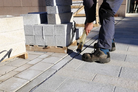 Chantier extérieur de pose de pavés par un ouvrier en tenue de travail